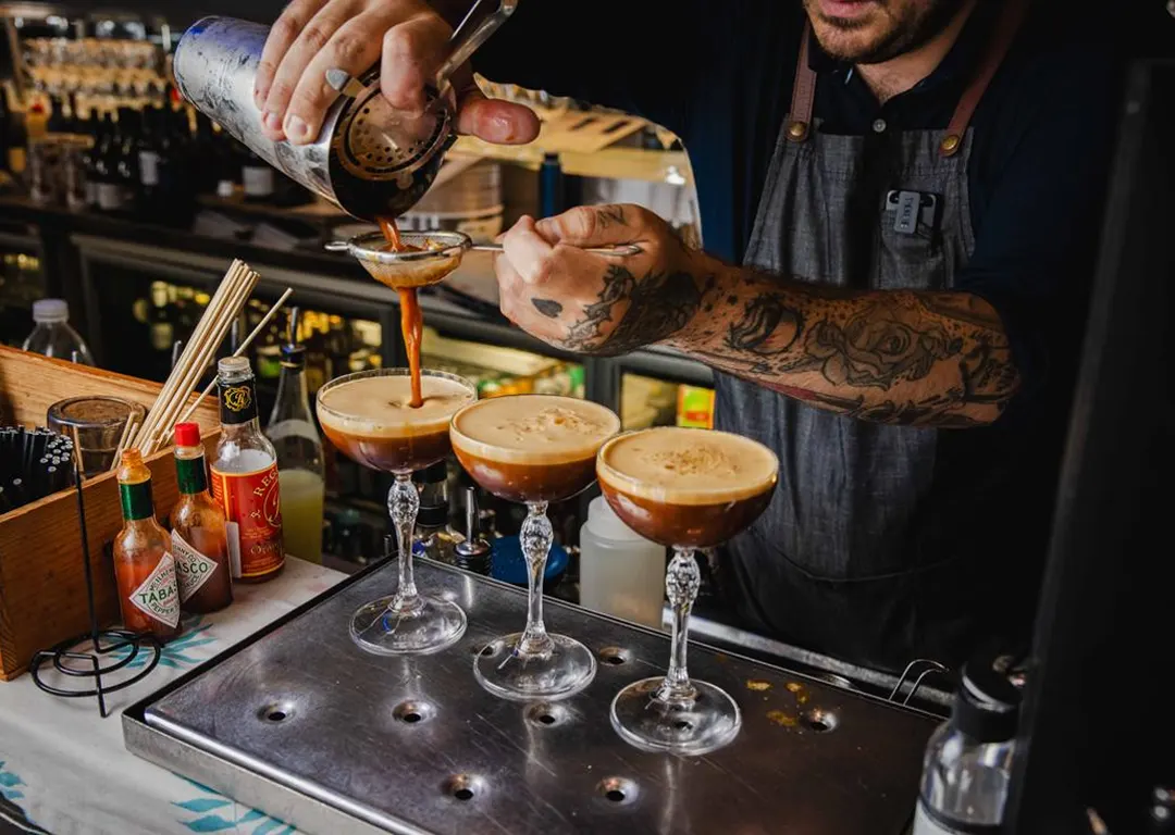 A Mudbar mixologist straining a cocktail